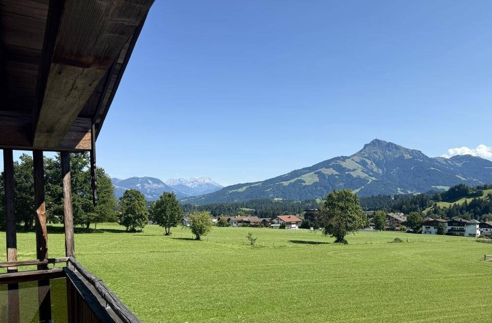 Balkon mit Blick auf grüne Wiesen und die majestätische Berglandschaft im Sonnenschein.
