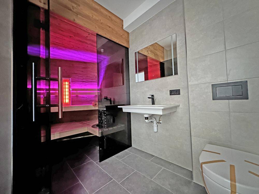 Modernes Badezimmer mit integrierter Sauna, Fliesenboden und Wand-WC.