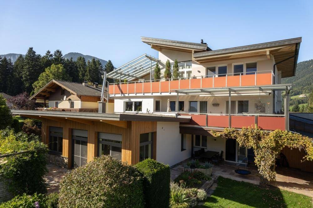 Moderne Architektur des Hauses mit mehreren Balkonen und Terrassen, umgeben von üppiger Vegetation.