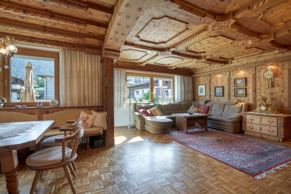 Traditionelles Wohnzimmer mit aufwendiger Holzvertäfelung, Holzbalkendecke und gemütlicher Einrichtung.