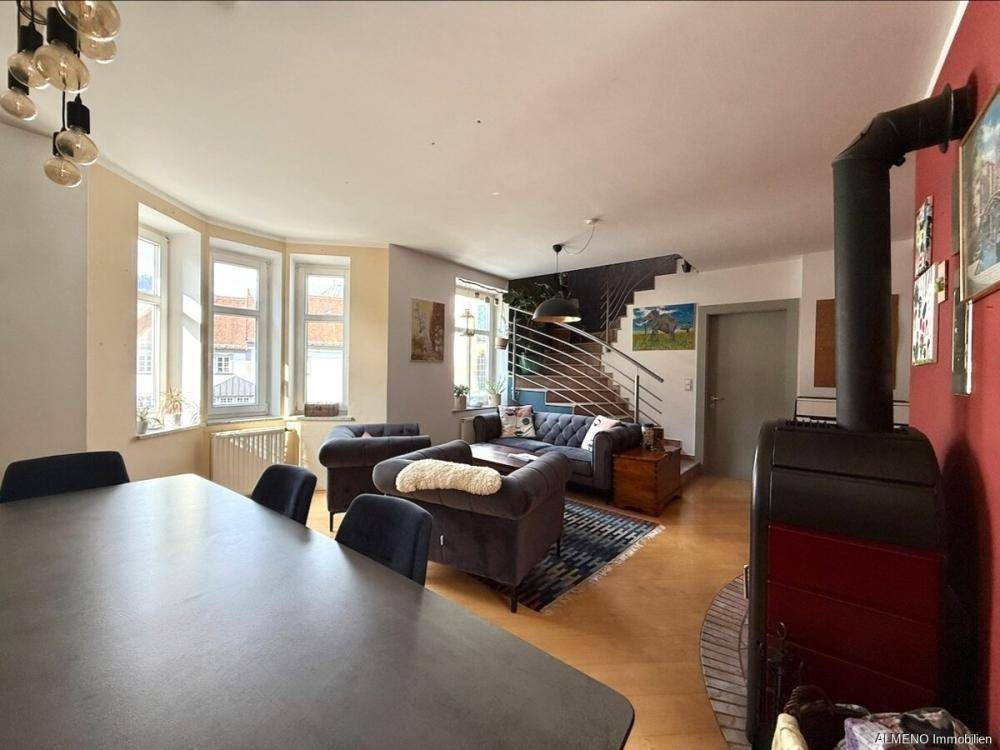 Heller Wohn-Essbereich mit Holzboden, Kaminofen und Erkerfenstern für viel Tageslicht.