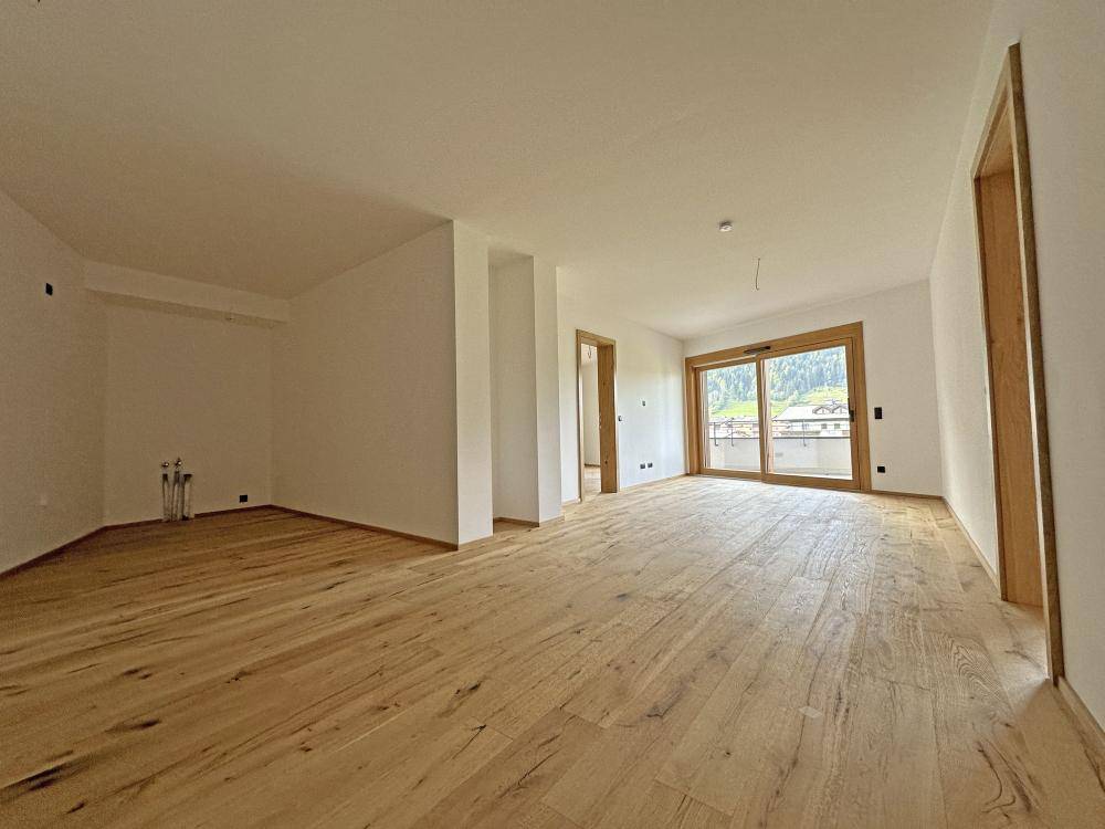 Heller Wohnbereich mit Holzboden und Zugang zu einem Außenbereich, noch im Bau.