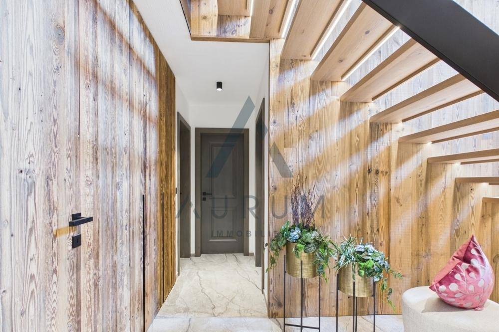 Heller Flur mit Holzvertäfelung, moderner Treppe und dekorativen Pflanzen.