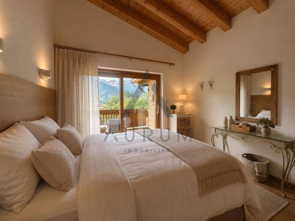 Helles Schlafzimmer mit Holzbalkendecke, großem Bett und Balkonzugang mit Panoramablick auf die Berge.