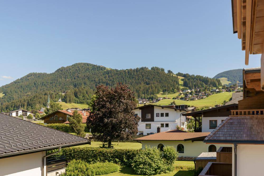 Malerischer Blick auf ein Dorf in den grünen Hügeln unter blauem Himmel.