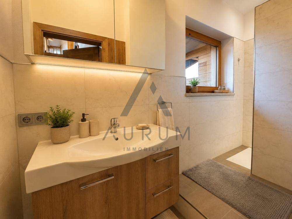 Modernes Badezimmer mit Waschtisch, Spiegelschrank, hellen Fliesen und Fenster für Tageslicht.