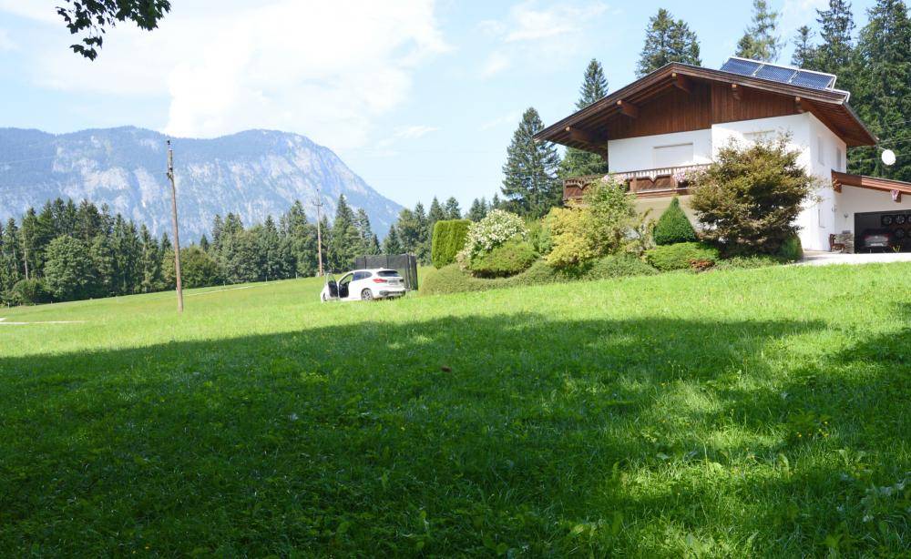 Attraktives Wohnhaus mit Holzdetails, Solaranlage, Balkon und weitem Panoramablick auf die Berge.