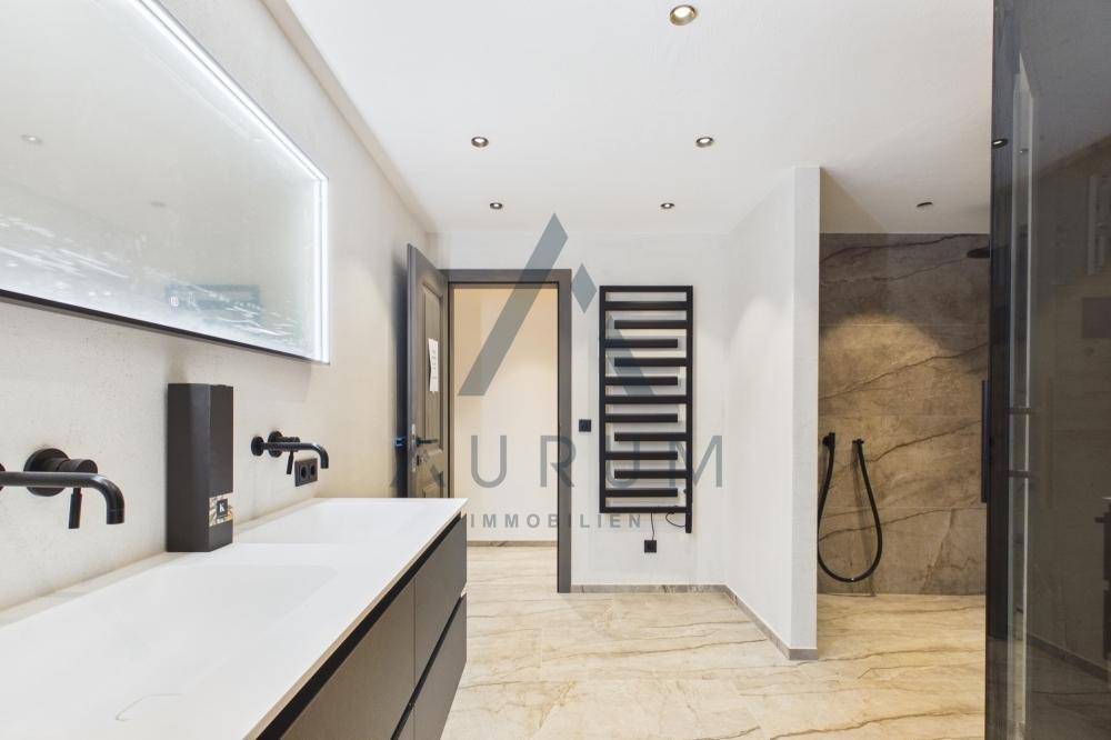 Geräumiges Badezimmer mit Doppelwaschbecken, beheiztem Handtuchhalter und begehbarer Dusche.