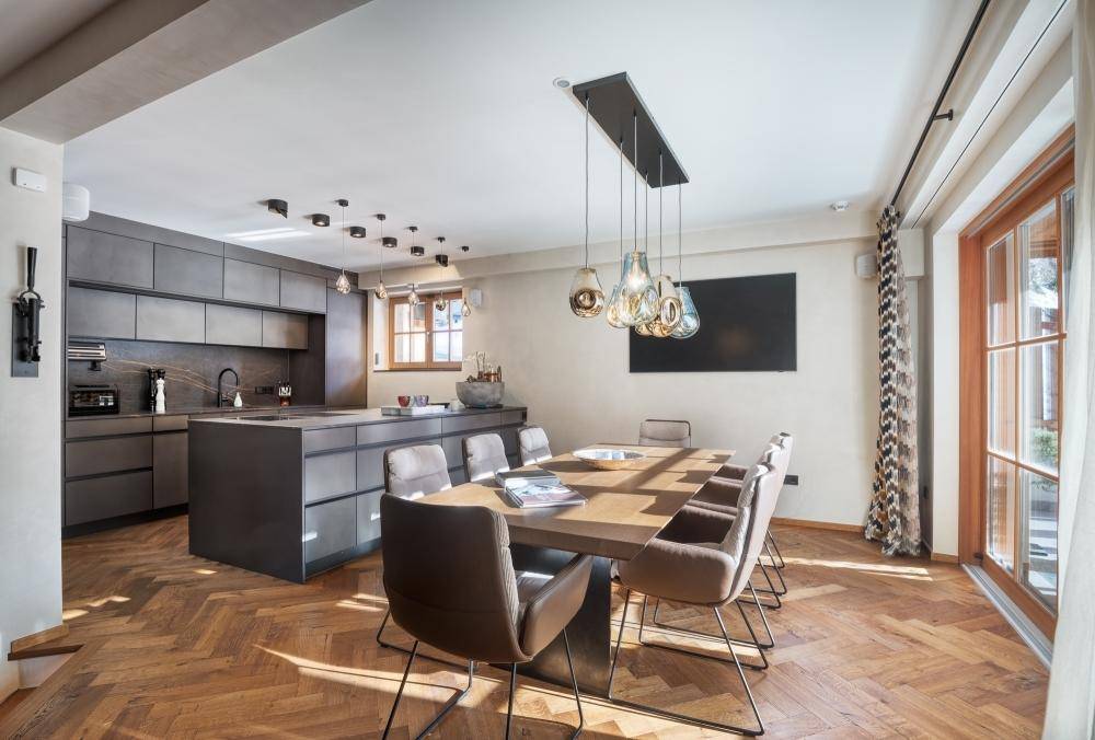 Moderne Küche mit Kücheninsel und angrenzendem Essbereich, ausgestattet mit stilvollen Pendelleuchten.