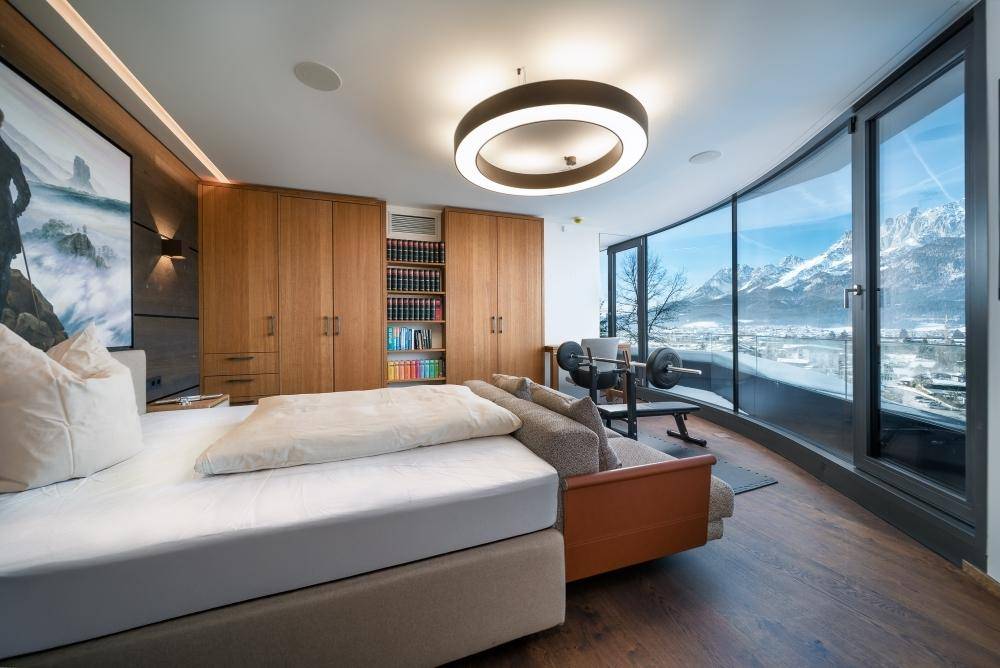 Schlafzimmer mit integriertem Fitnessbereich und Panoramafenstern mit Bergblick.