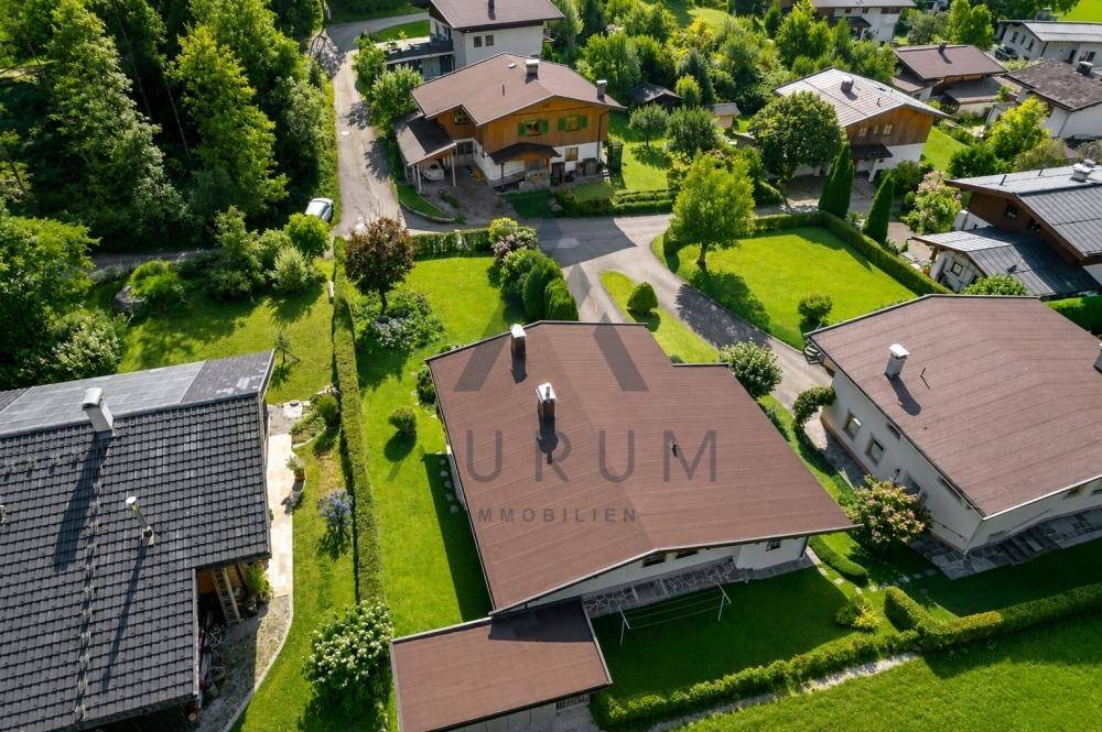 Vogelperspektive eines Einfamilienhauses mit braunem Dach, umgeben von einem gepflegten Garten und Hecken.