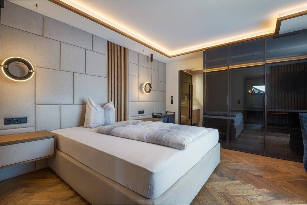 Modernes Schlafzimmer mit gepolstertem Kopfteil, Einbauschränken und indirekter Deckenbeleuchtung.