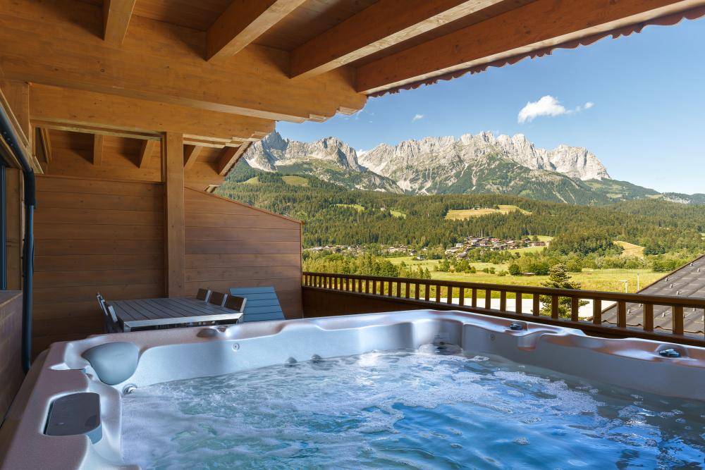 Großer Balkon mit Whirlpool und atemberaubendem Panoramablick auf die majestätischen Berge.