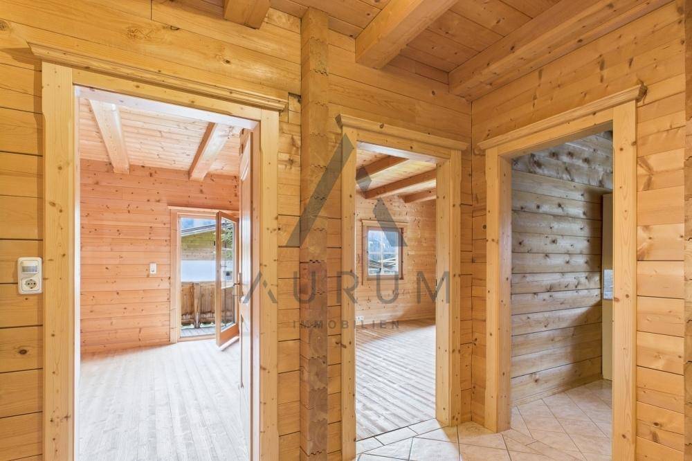 Rustikaler Flur mit Holzwänden und -decken, der zu weiteren Zimmern und einem Balkon führt.