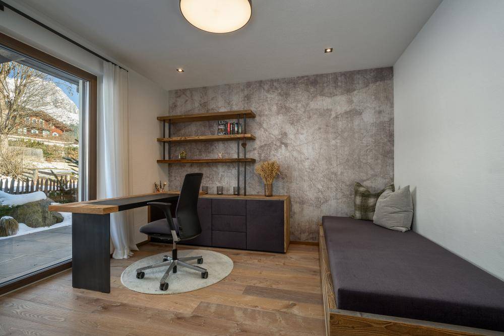 Helles Büro mit Holzboden, modernem Schreibtisch und Zugang zur Terrasse im Winter.