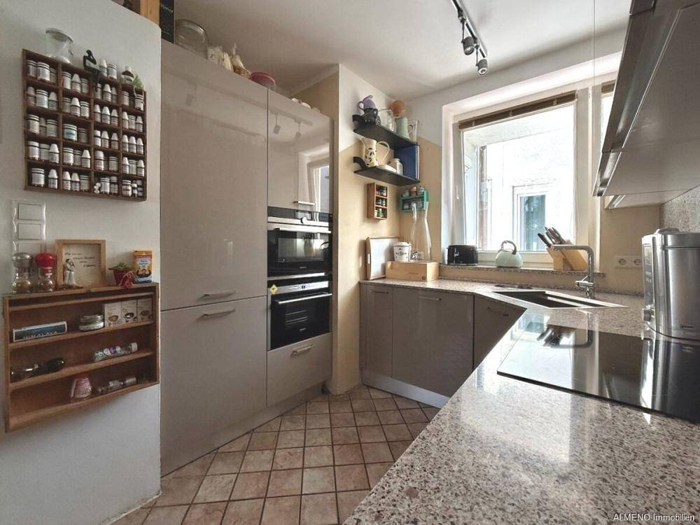 Funktionale Küche mit hellen Schränken, Granitarbeitsplatte und Fliesenboden.
