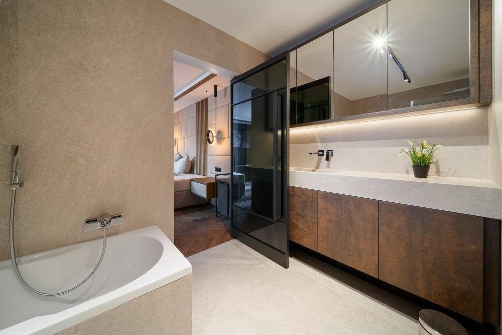 Modernes En-Suite-Badezimmer mit Badewanne und elegantem Waschtisch, verbunden mit dem Schlafzimmer.