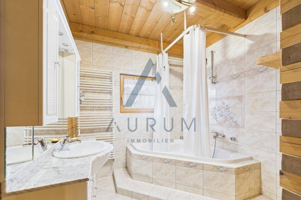 Helles Badezimmer mit Eckbadewanne, Duschfunktion, Marmorwaschtisch und beheiztem Handtuchhalter.