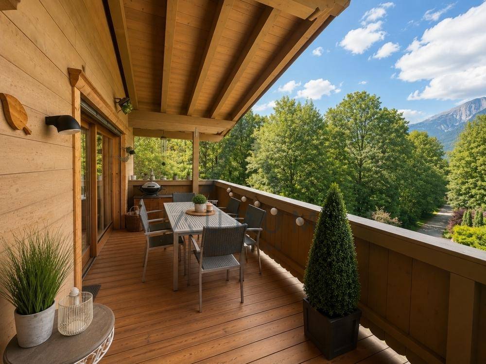 Geräumiger Balkon mit Esstisch und Stühlen, umgeben von Bäumen und mit Blick ins Grüne.