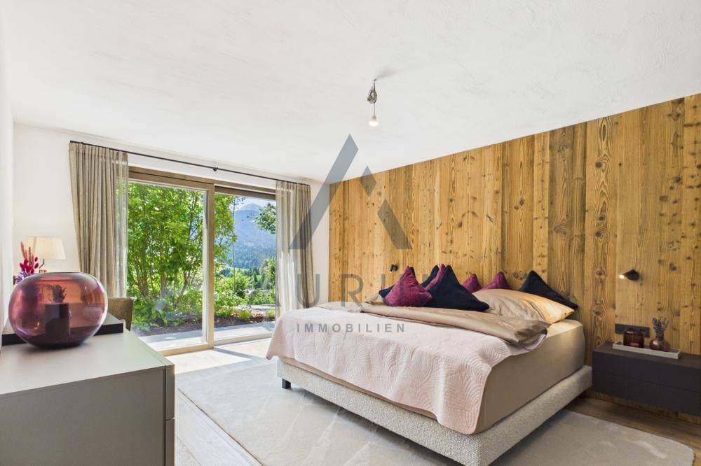 Helles Schlafzimmer mit Holzwand, Zugang zum Garten und Blick auf die Berge.