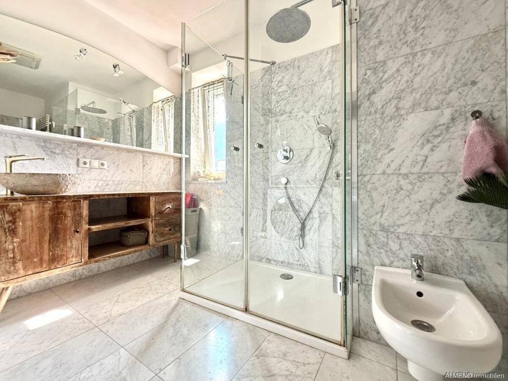 Modernes Badezimmer mit begehbarer Dusche, Bidet und eleganten Marmorfliesen.