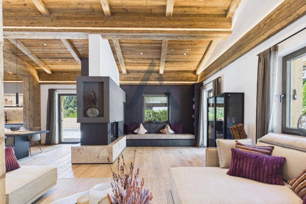 Gemütliches Wohnzimmer mit Holzbalkendecke, modernem Kamin und integrierter Sitzbank am Fenster.