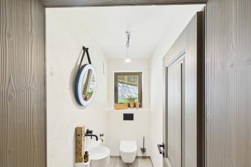 Modernes Gäste-WC mit kleinem Waschbecken, Wand-WC und Fenster.