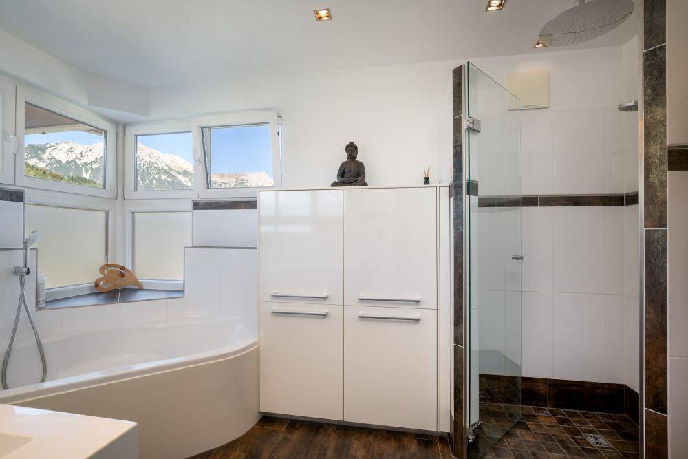 Modernes Badezimmer mit Duschkabine, Eckbadewanne und Fenstern, die einen Bergblick bieten.