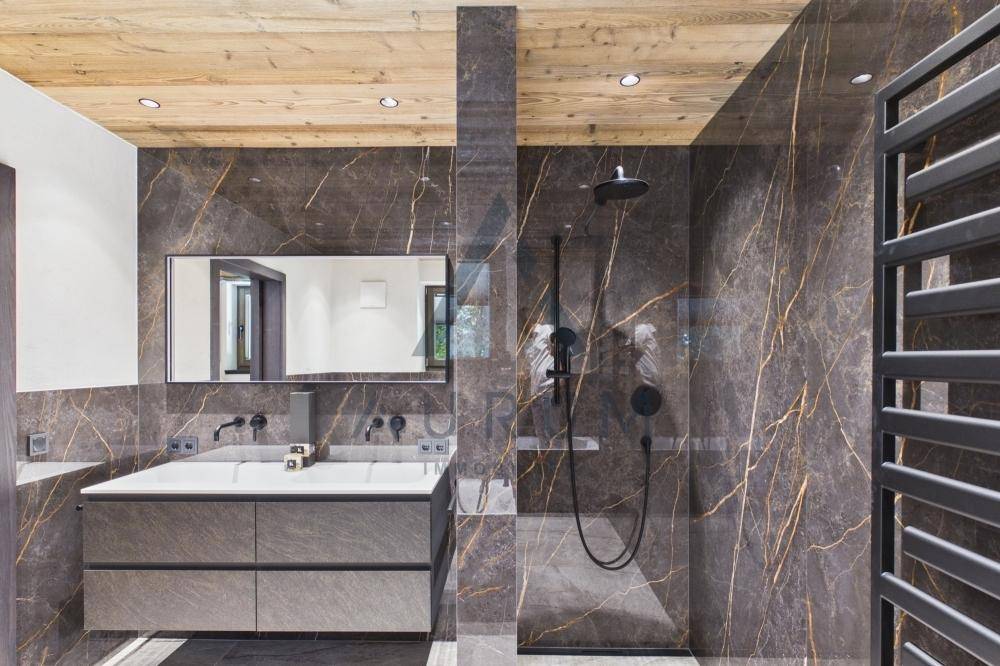 Modernes Badezimmer mit dunklen Marmorfliesen, Doppelwaschbecken und begehbarer Dusche.