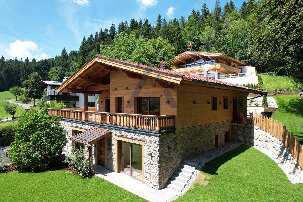 Charmantes Holzhaus im alpinen Stil mit Steinfassade, großem Garten und umlaufendem Balkon.