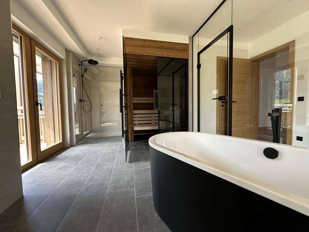 Modernes Badezimmer mit freistehender Badewanne, begehbarer Dusche und integrierter Sauna.