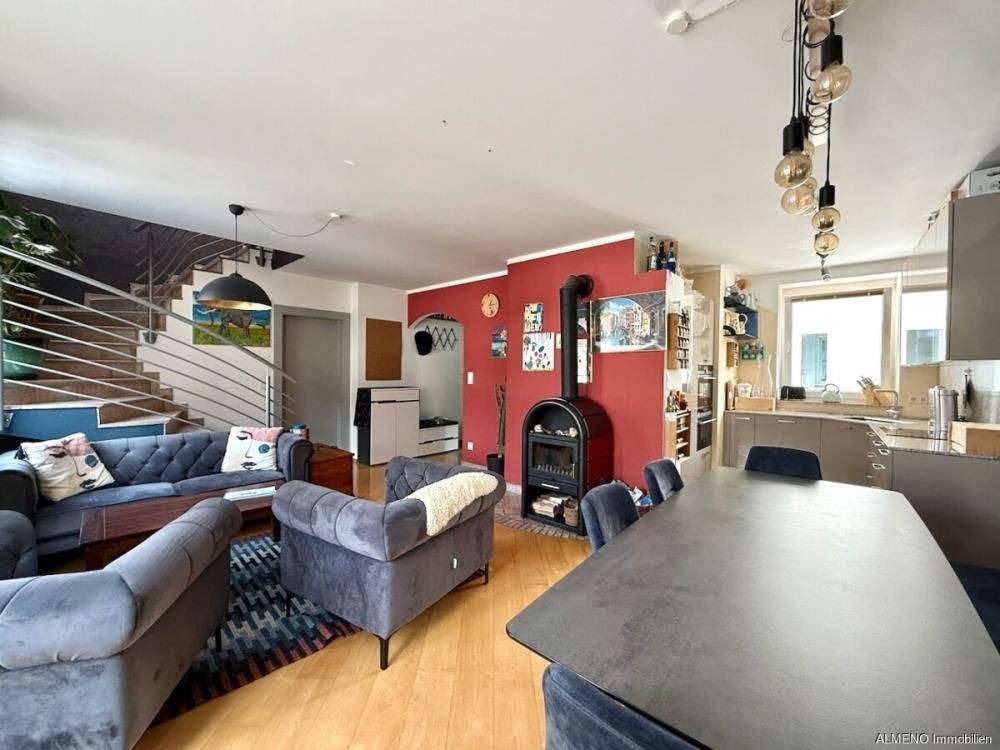 Gemütlicher offener Wohn-Essbereich mit Kaminofen, Holzfußboden und moderner Treppe.