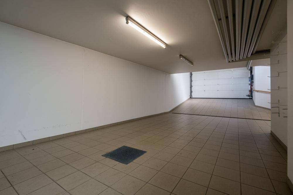 Helle Tiefgarage mit Fliesenboden und Rolltor für mehrere Fahrzeuge.