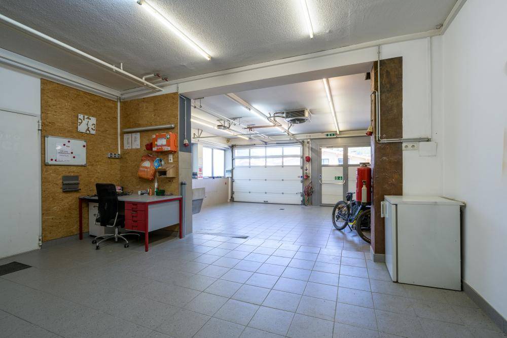 Geräumige Garage mit Werkstattbereich, Fliesenboden und Rolltor.