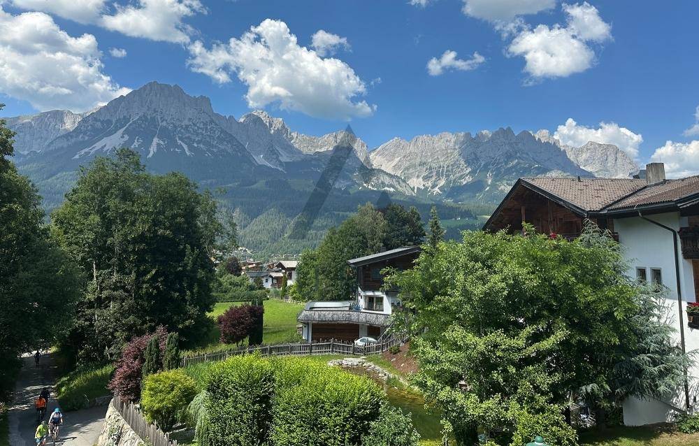 Malerische Umgebung mit traditionellen Häusern, üppiger Vegetation und majestätischem Bergblick.