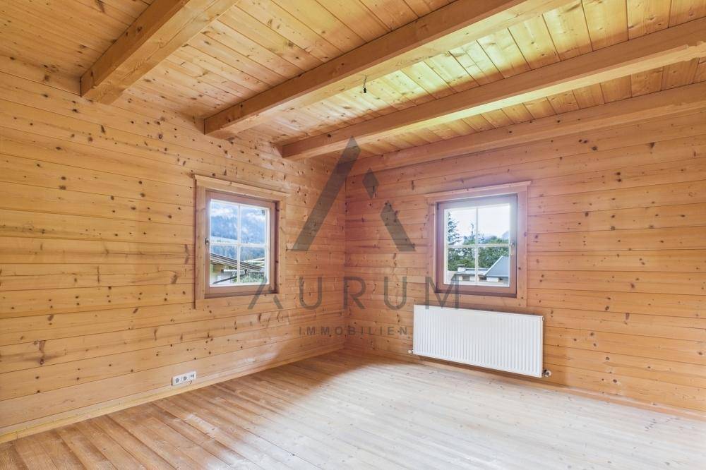 Gemütliches Zimmer mit Holzwänden, Holzboden und Fenstern, die einen schönen Bergblick bieten.