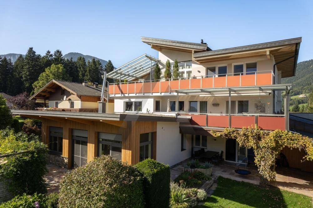 Moderne Architektur des Hauses mit mehreren Balkonen und Terrassen, umgeben von üppiger Vegetation.
