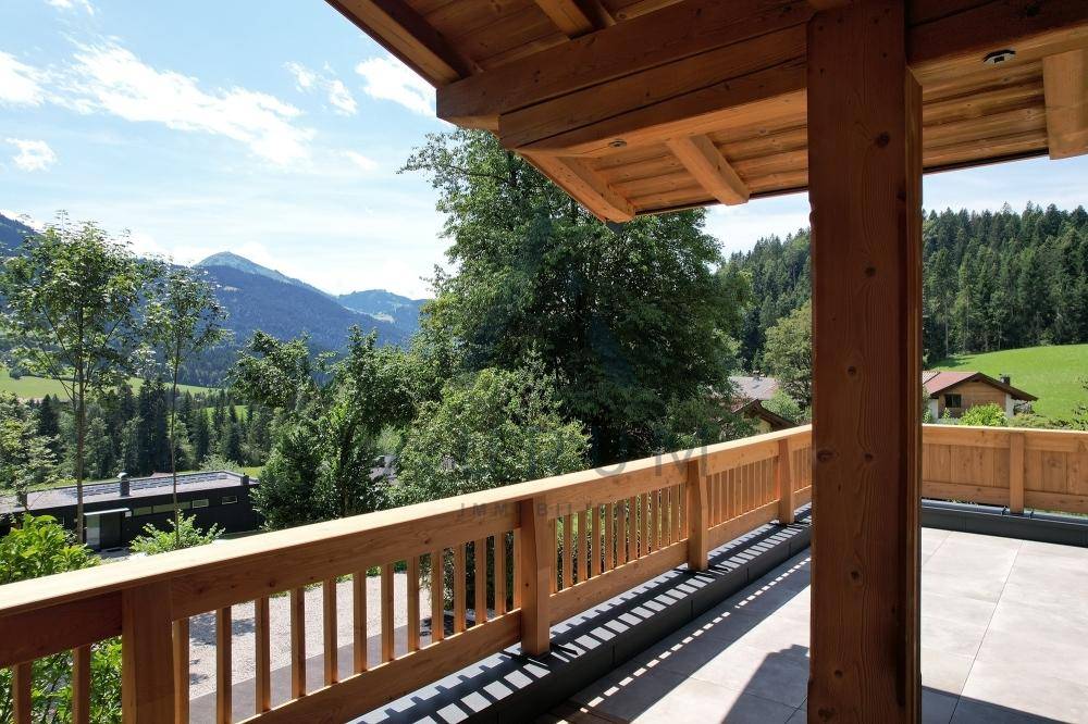 Überdachte Terrasse mit Holzbalken und weitem Blick auf die bewaldeten Berge.
