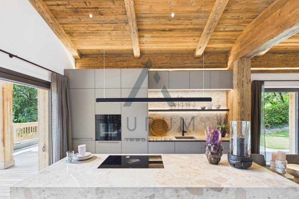 Elegante Küche mit heller Arbeitsplatte, integrierten Geräten und direktem Zugang zur Terrasse.