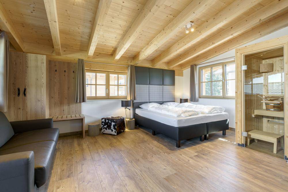 Geräumiges Schlafzimmer mit Holzbalkendecke, Doppelbett und integrierter Sauna für Entspannung.