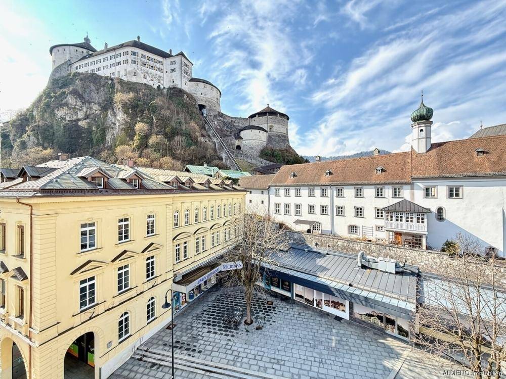 Blick auf die historische Stadt mit imposanter Burg auf dem Hügel und belebtem Platz.