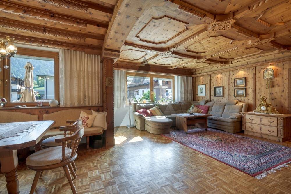 Gemütlicher Wohn-Essbereich im alpinen Stil mit aufwendigen Holzvertäfelungen, geschnitzter Decke und Parkettboden.