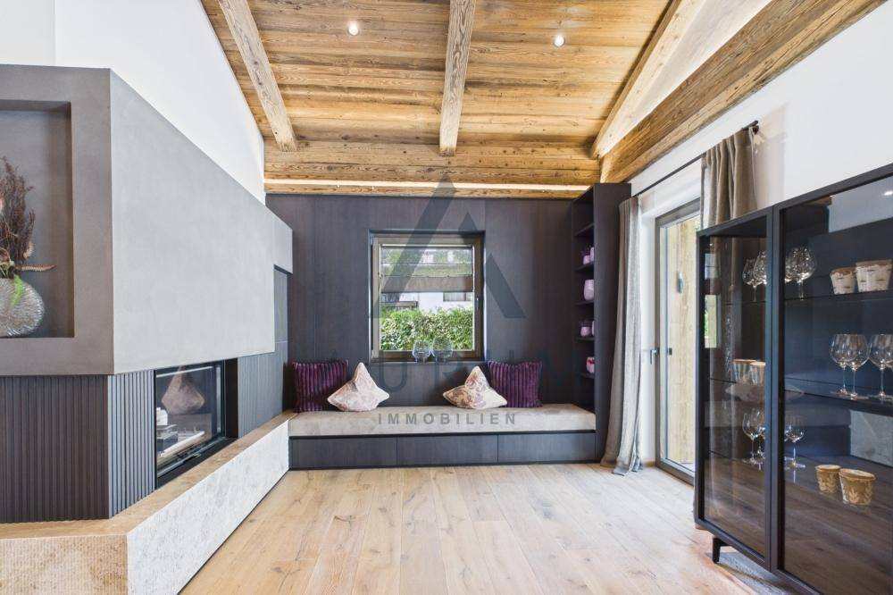 Stilvolles Wohnzimmer mit Kamin, Holzbalkendecke und einer gemütlichen Sitznische am Fenster.