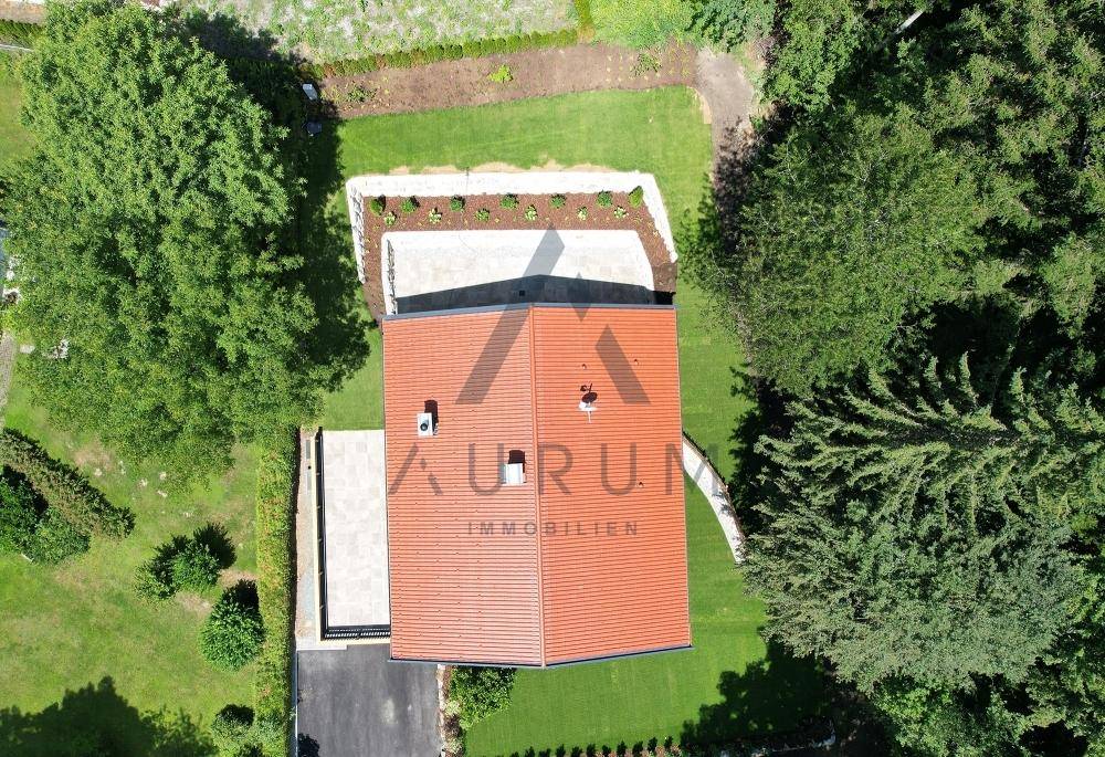 Luftaufnahme des Hauses mit rotem Dach, umgeben von grünen Bäumen und Gartenflächen.