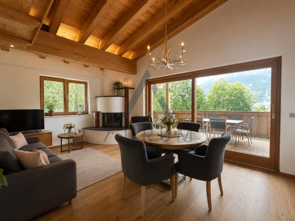 Gemütlicher Wohn-Essbereich mit Holzbalkendecke, Kamin und Zugang zu einem Balkon mit Bergblick.