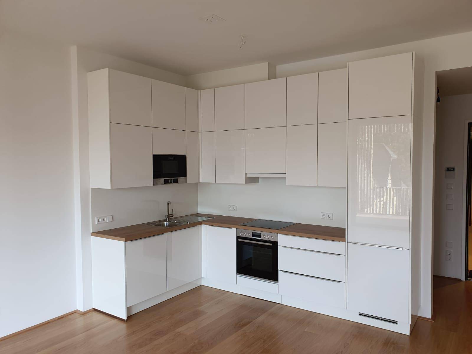 Moderne Einbauküche in Weiß mit Holz-Arbeitsplatten und integrierten Geräten.