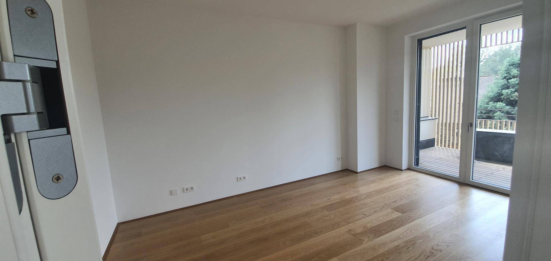 Helles Schlafzimmer mit Holzboden und direktem Zugang zu einem privaten Balkon.