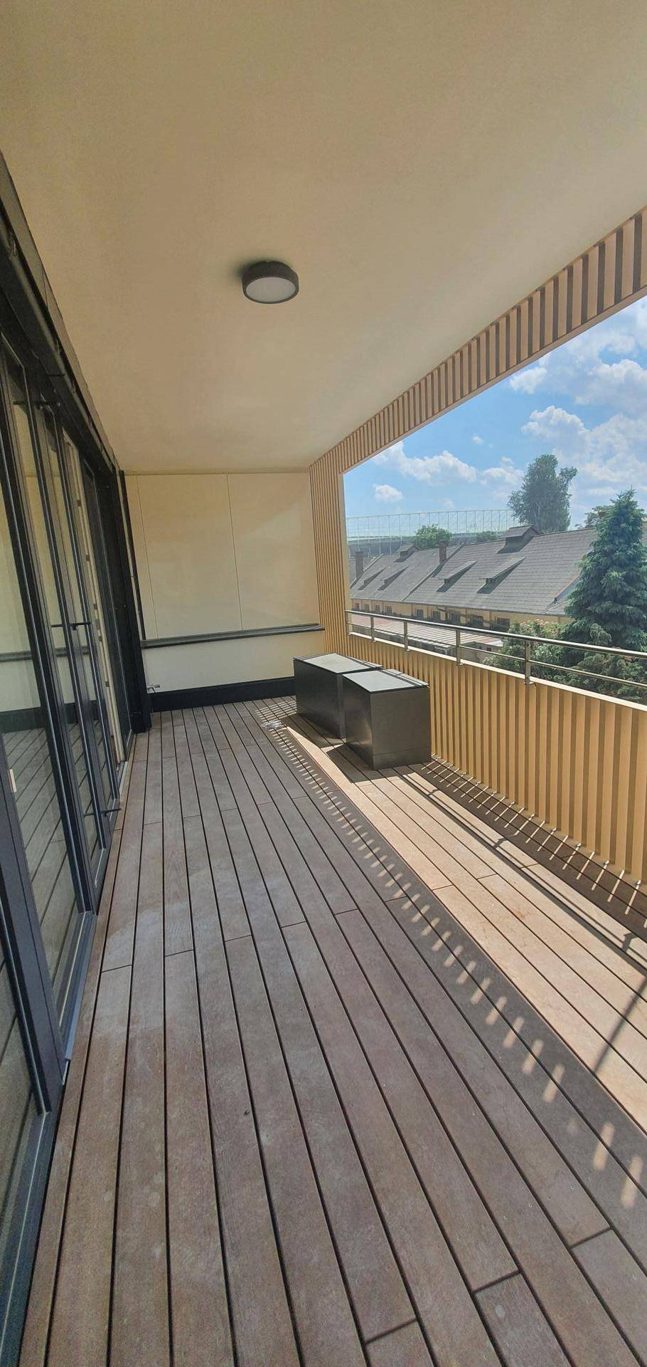 Heller Balkon mit Holzdielen und viel Sonnenlicht, ideal für entspannte Stunden im Freien.
