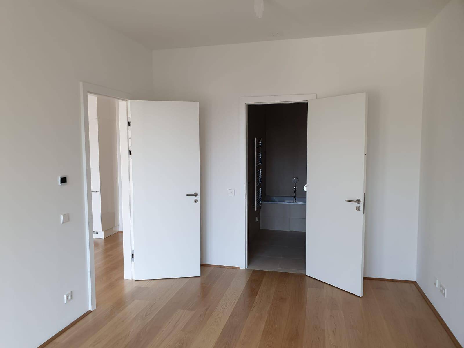 Geräumiges Zimmer mit Holzboden und direktem Zugang zu einem angrenzenden Badezimmer.