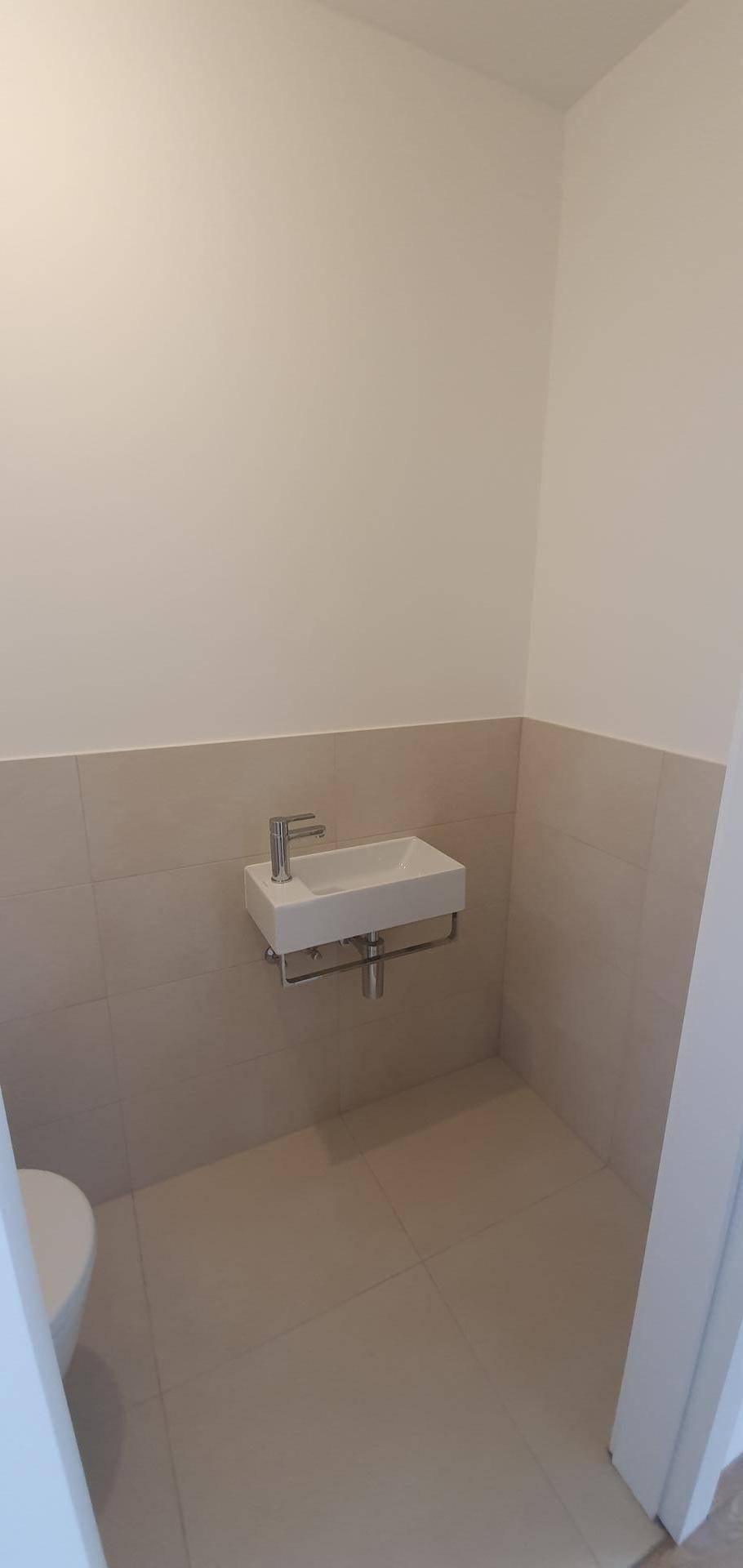 Kompaktes Gäste-WC mit wandhängender Toilette und kleinem Waschbecken.